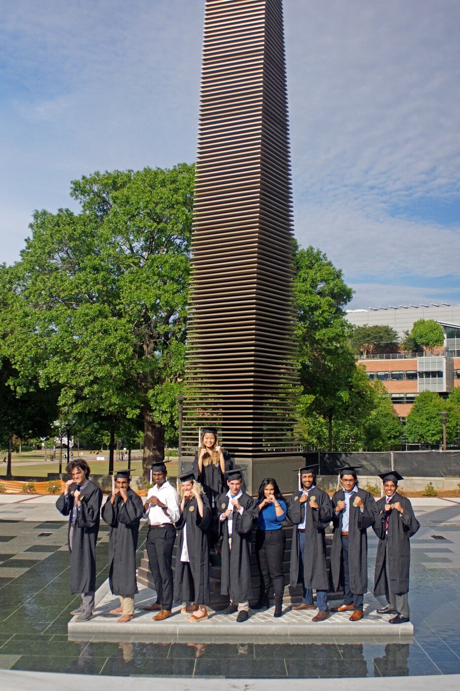 Friends celebrating graduation in caps and gowns on campus