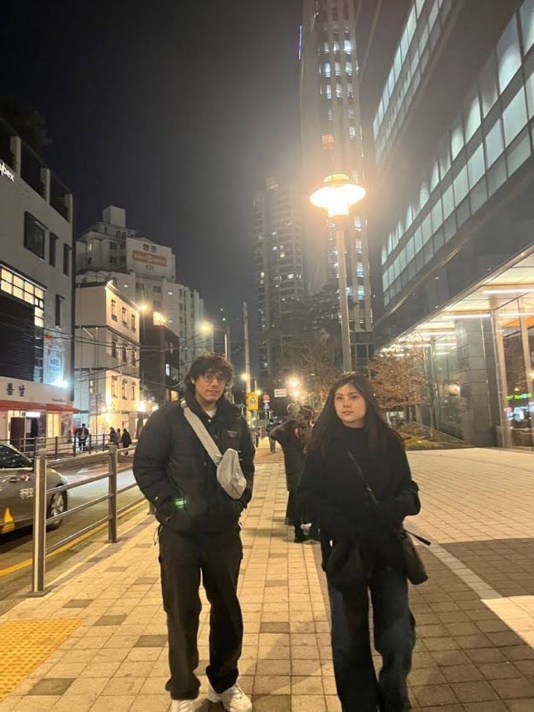 Two friends standing together on a city street at night