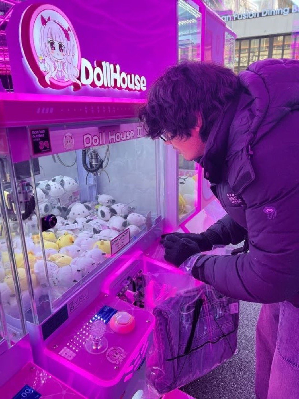 A person playing a brightly lit claw machine