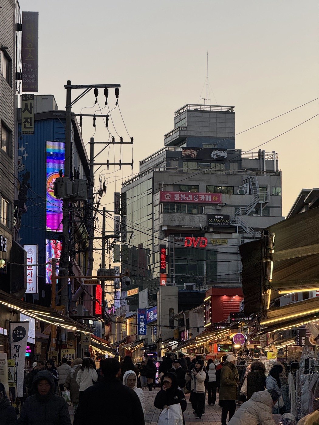 A crowded market street lined with Korean shop signs