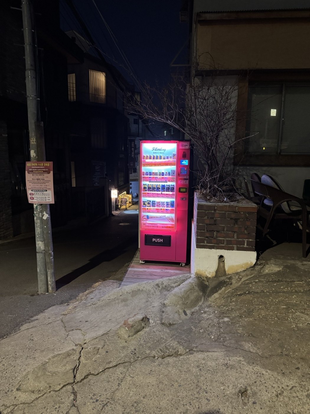 A bright pink vending machine in a small alley