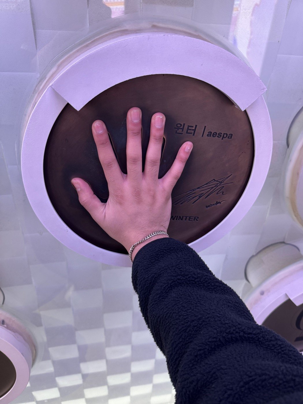 A hand resting against a signed handprint display in Korea