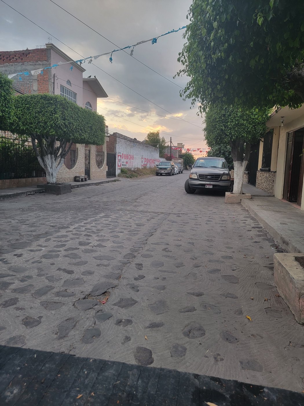 A cobblestone neighborhood street in Mexico at sunset