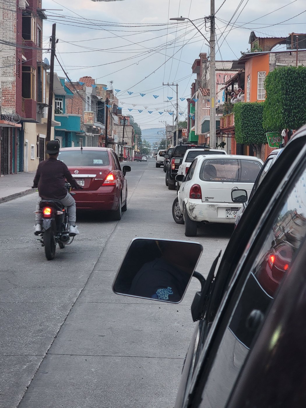 Cars and a motorcycle traveling along a neighborhood street