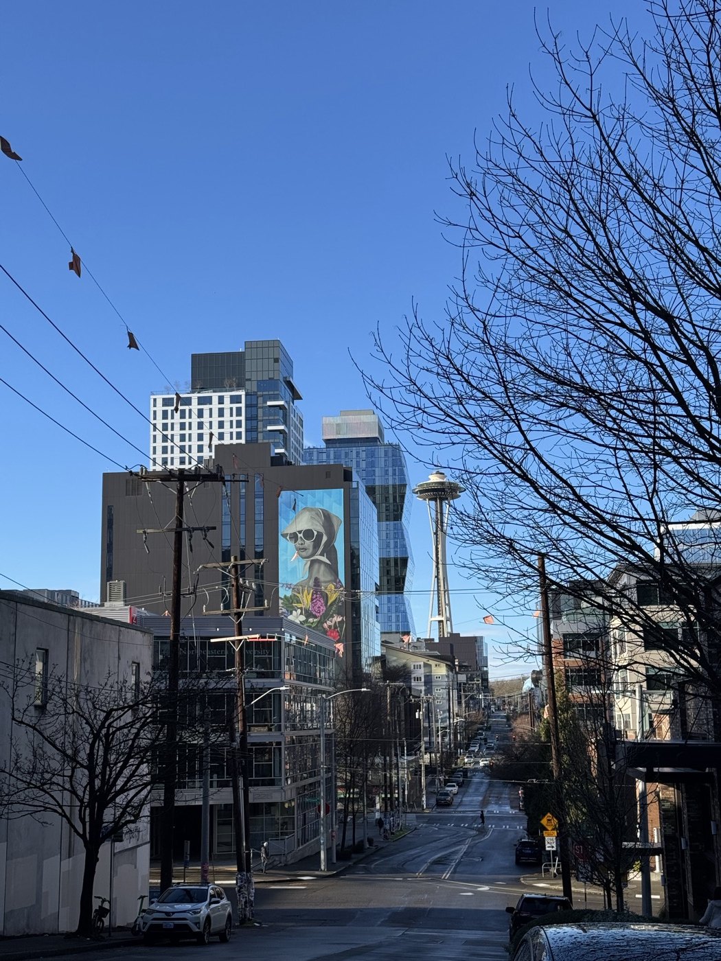 The Space Needle at the end of a Seattle street beneath a clear blue sky
